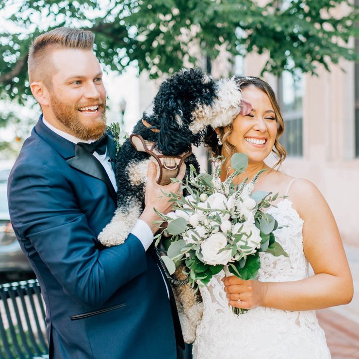 happy newlywed couple holding their dog