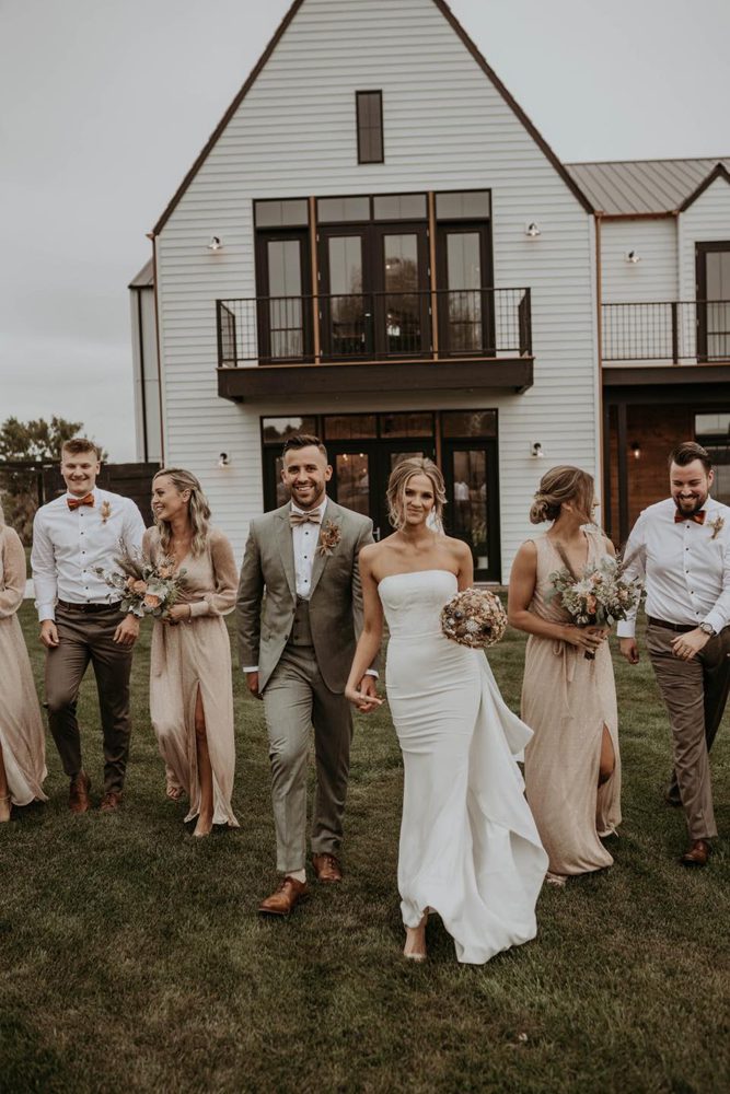 newlywed couple walking together with their bridesmaid and bridegroom