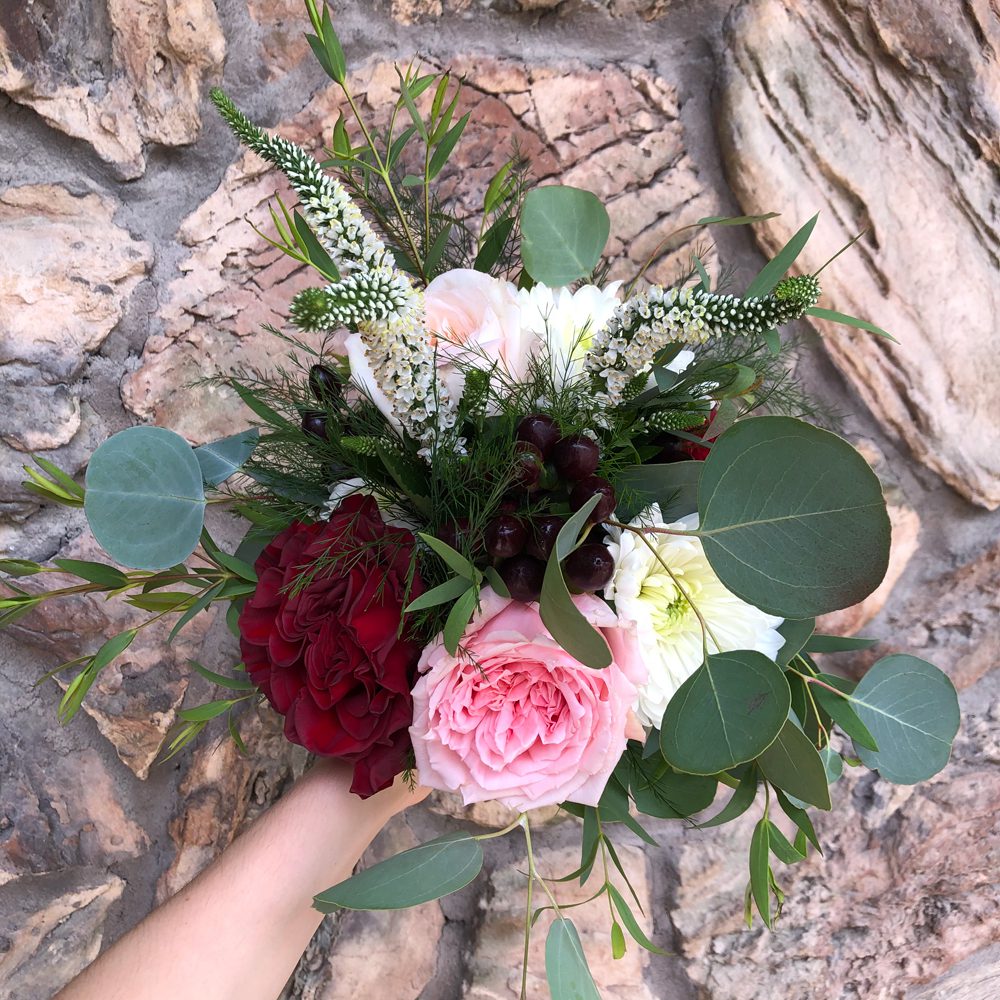 bouquet of white, red, and rose-pink flowers and leaves, beautiful hardscape as background