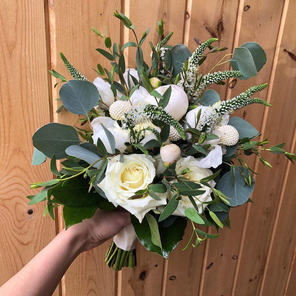 holding a bouquet of white flowers and buds with beautiful leaves