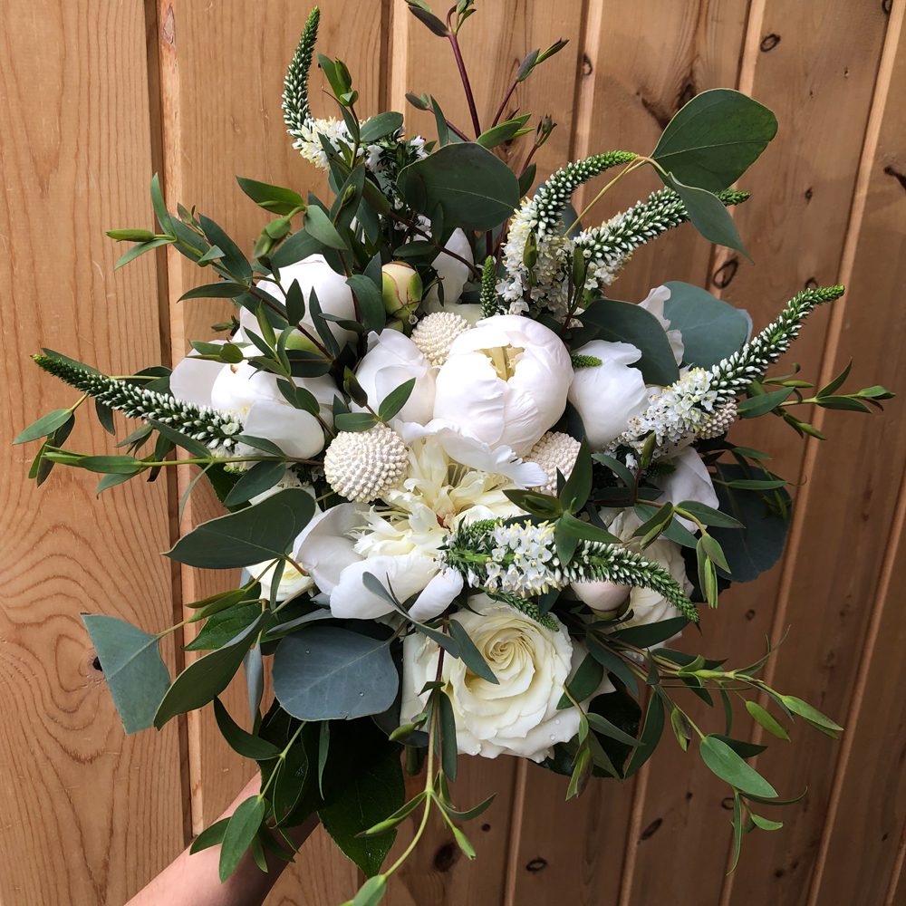 holding a bouquet of white flowers and buds