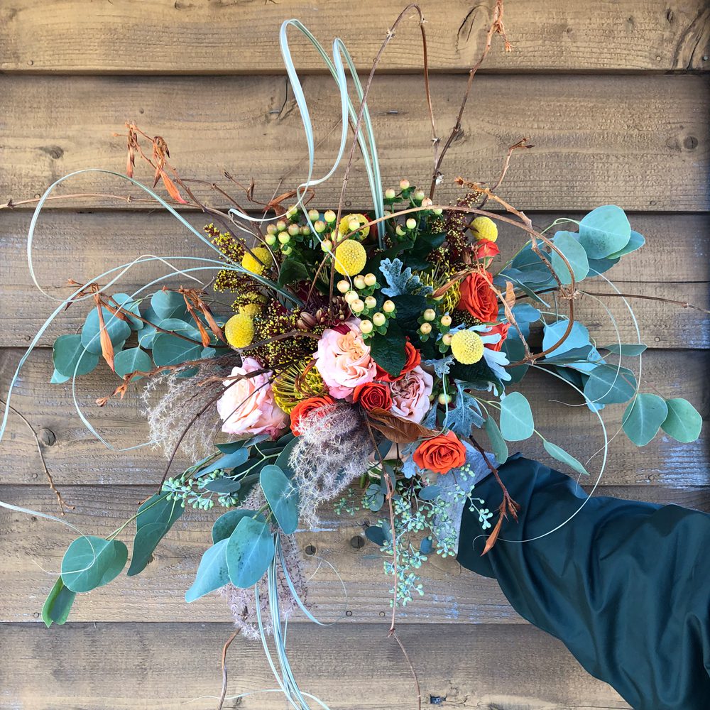 holding a bouquet of fall-themed flowers